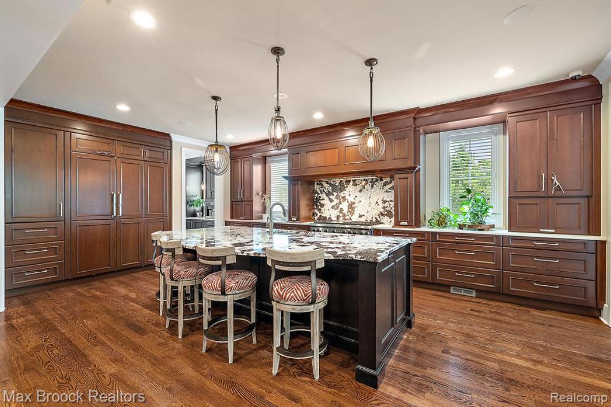 Kitchen with a large island, wood flooring, custom lights and custom cabinets.