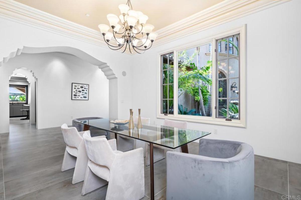 Dining room with a glass table, chairs and a chandelier.