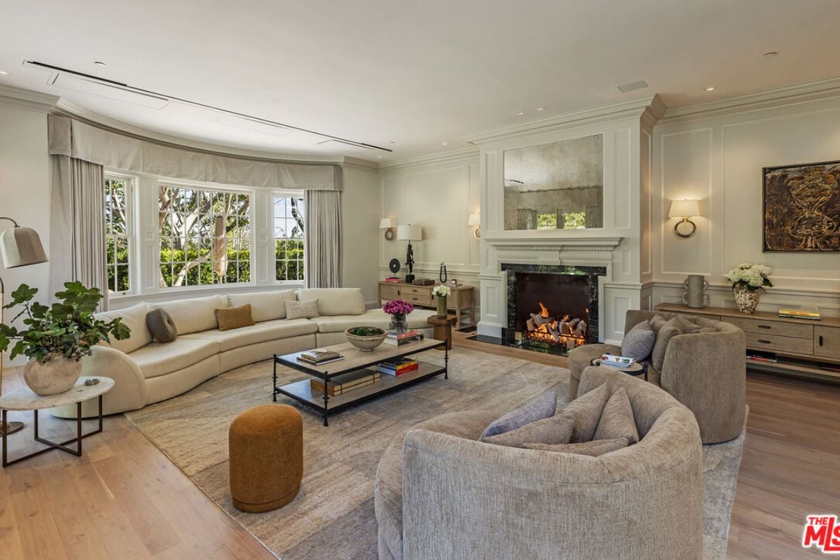 A living room with a fireplace, windows, couches, and a center table.