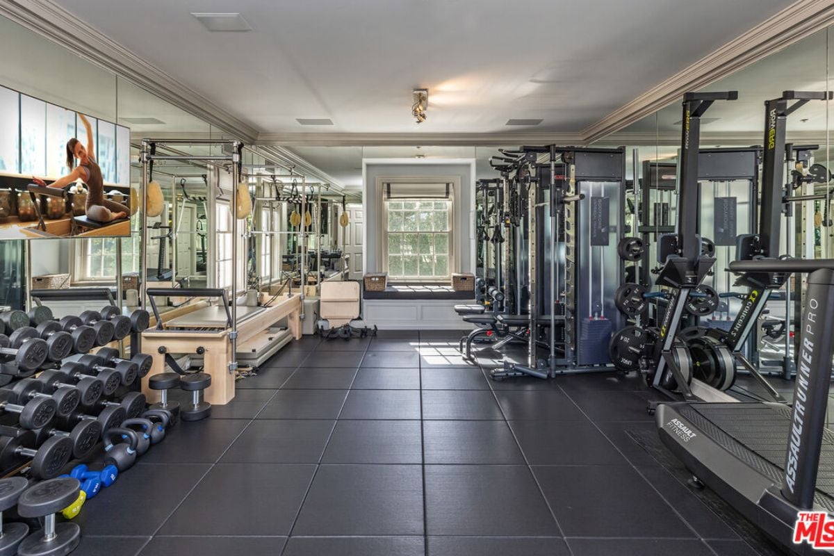 A home gym with a tiled floor, TV, and gym equipment.