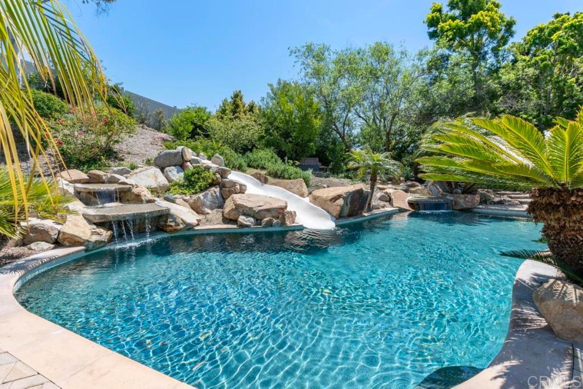 Pool with a slide and a man-made waterfalls.