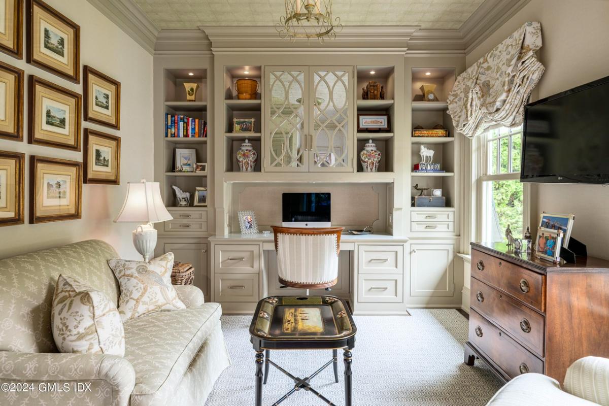 Home office with carpet flooring, sofa and shelves.