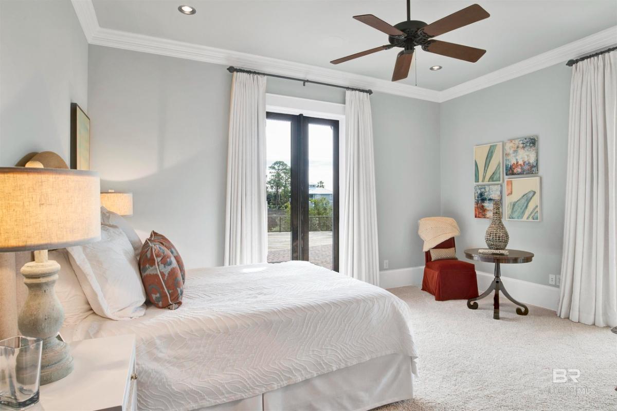 Bedroom with carpet flooring, ceiling fan and glass doors.