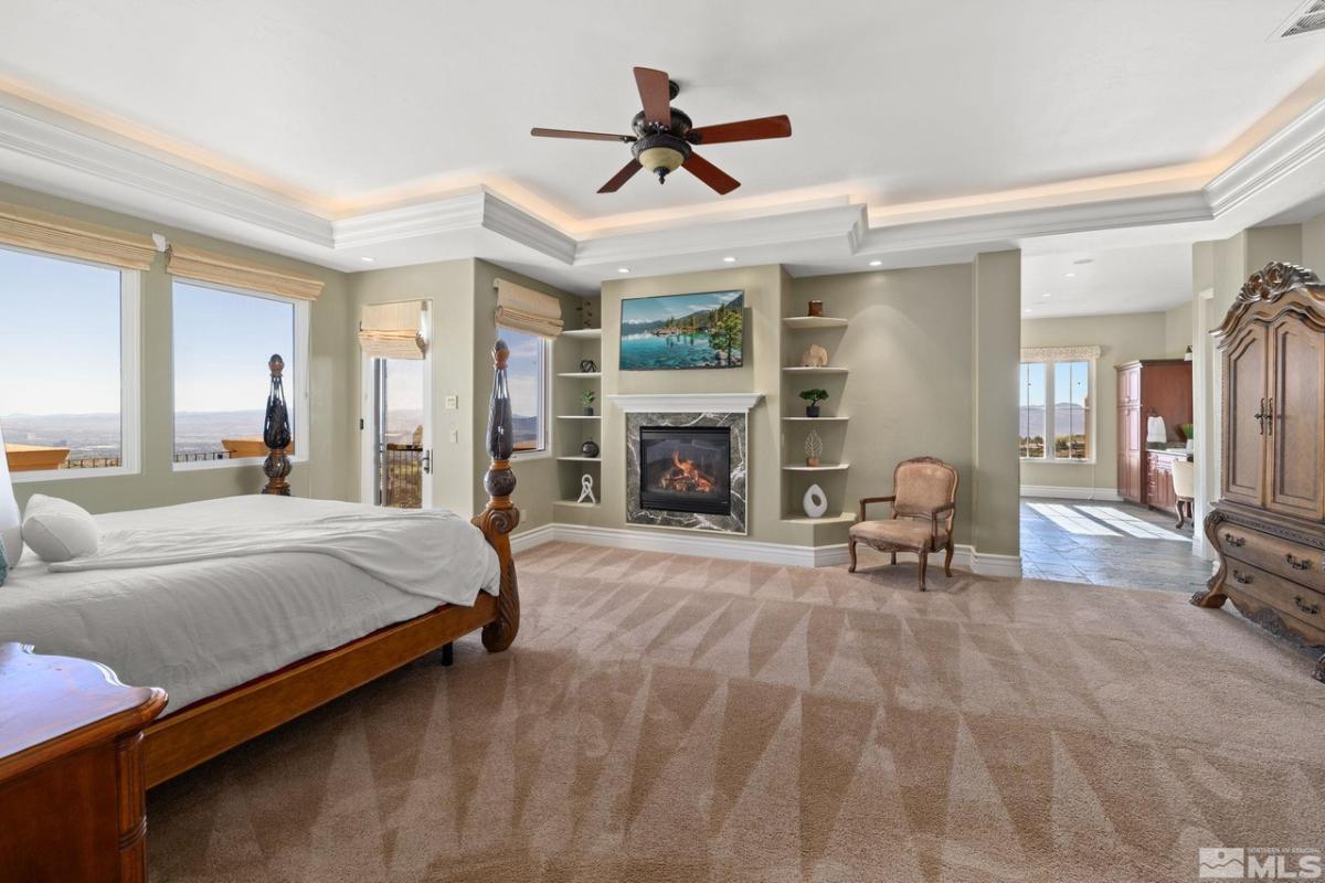 Bedroom with carpet floors, glass windows and a fireplace.