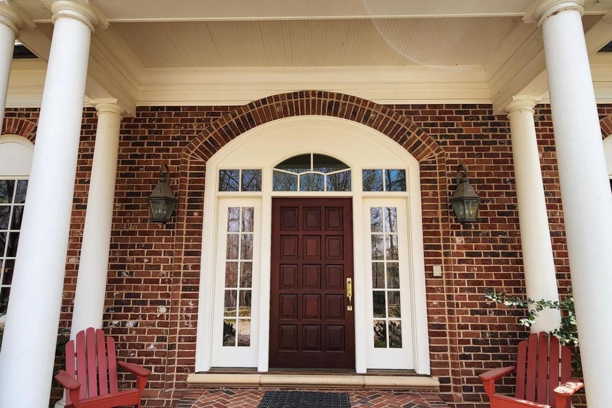 A front entry with a wooden door and brick walls.