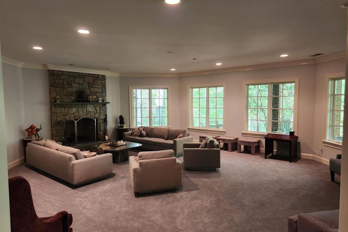 A living room with windows, a fireplace, chairs, couches, and a center table.