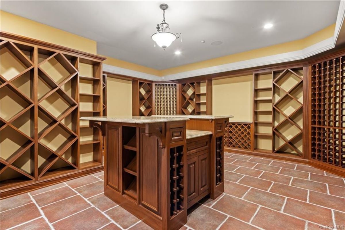 A wine cellar with a center island, a white ceiling, and wine racks.