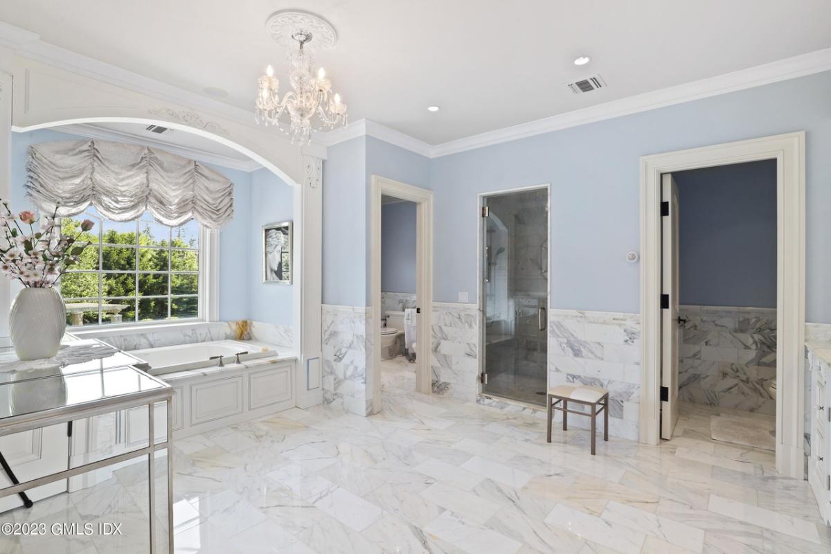 Bathroom with a soaking tub, toilet, shower room and a chandelier.