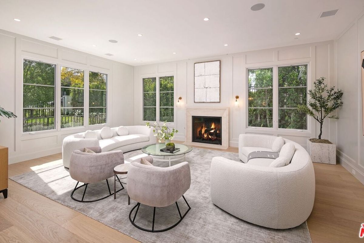 A living room with windows, white couches, a fireplace, and a center table.