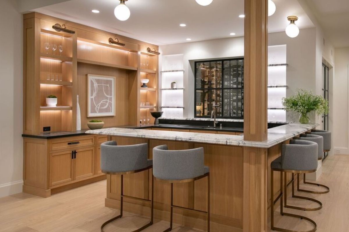 A bar with a countertop, stools, shelves, and wine racks.