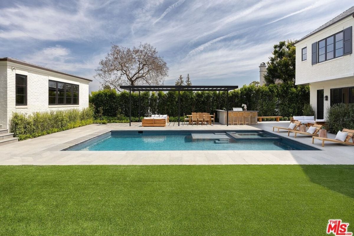 A swimming pool with chairs and a table on the poolside.
