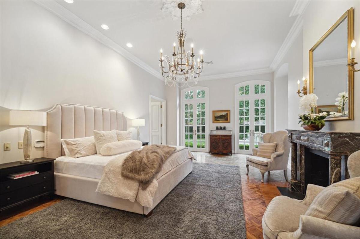 Bedroom with a chandelier, a large bed and a fireplace.
