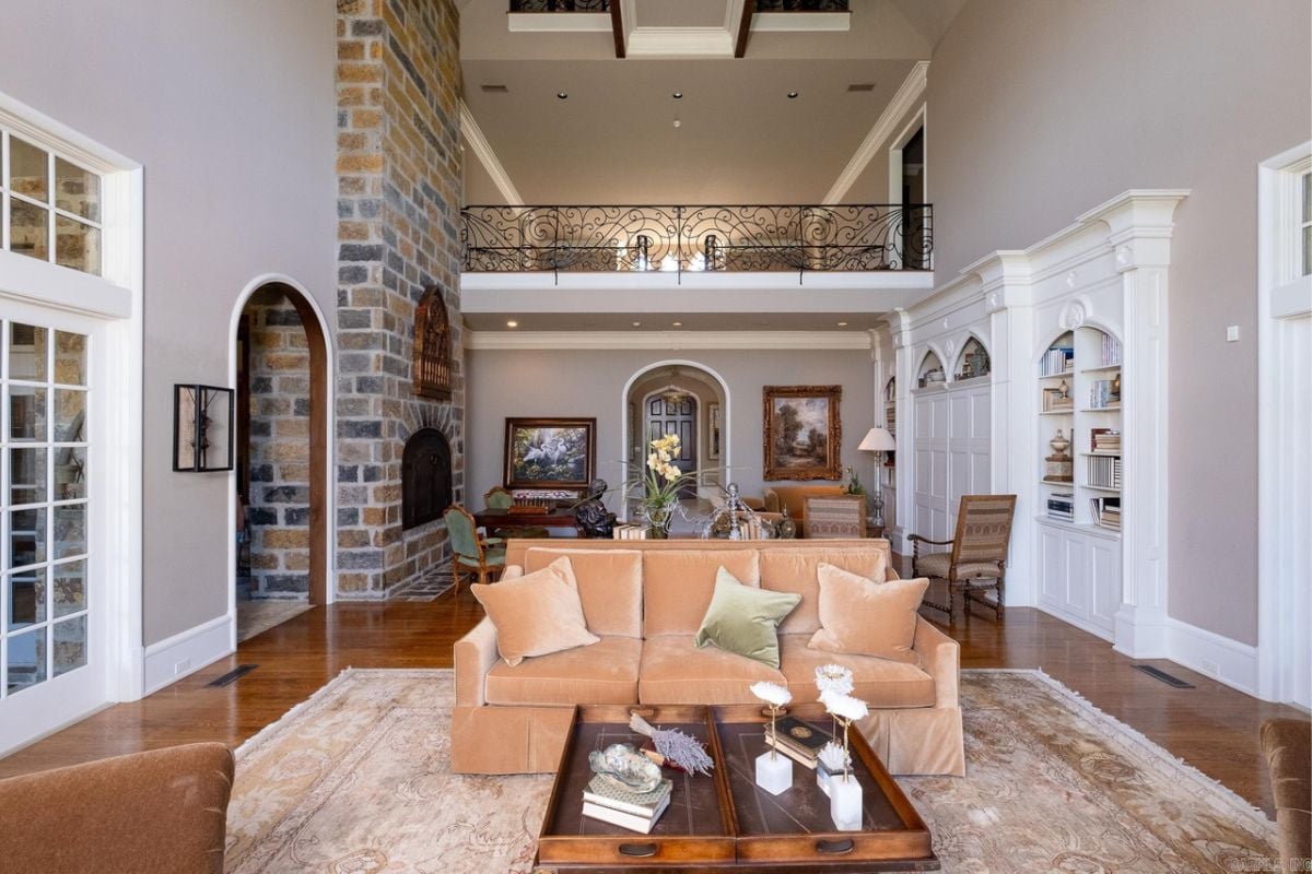 A living room with a couch, fireplace, shelves, and center table.