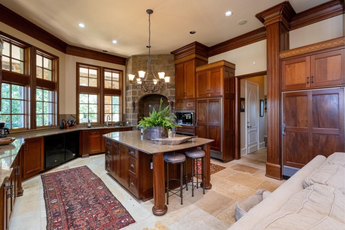 A kitchen with a center island, windows, cabinets, countertop, and kitchen appliances.