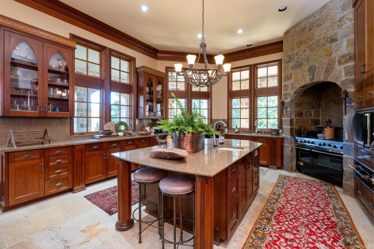 A kitchen with a center island, windows, cabinets, countertop, and kitchen appliances.