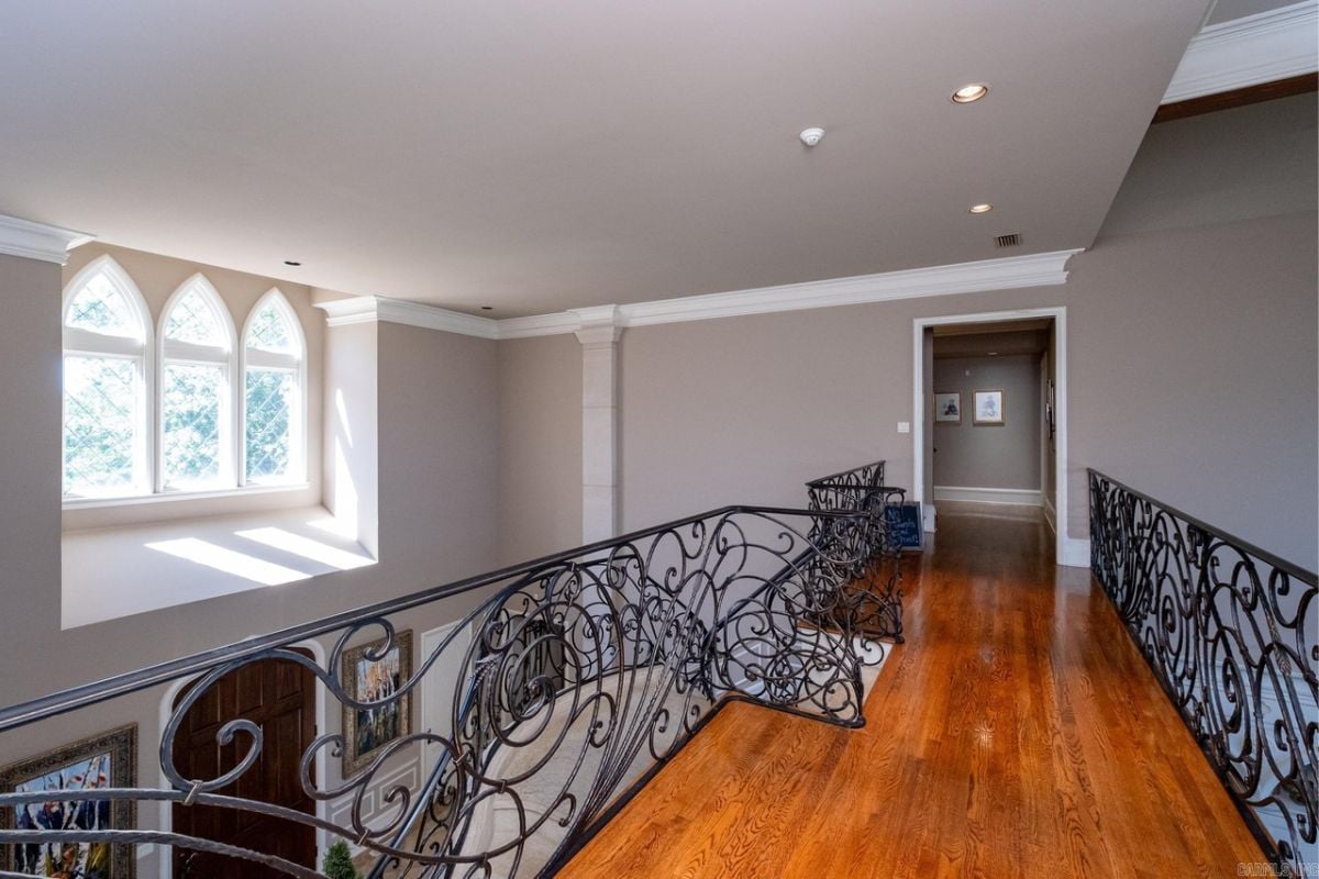 A landing with a metal handrail and wooden floor.