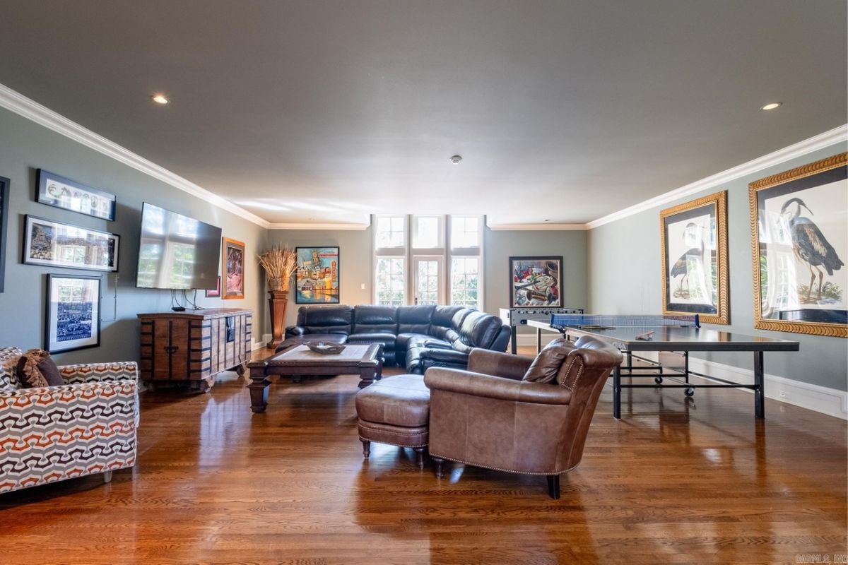 An entertainment room with a TV, paintings, couches, a center table, and a tennis table.