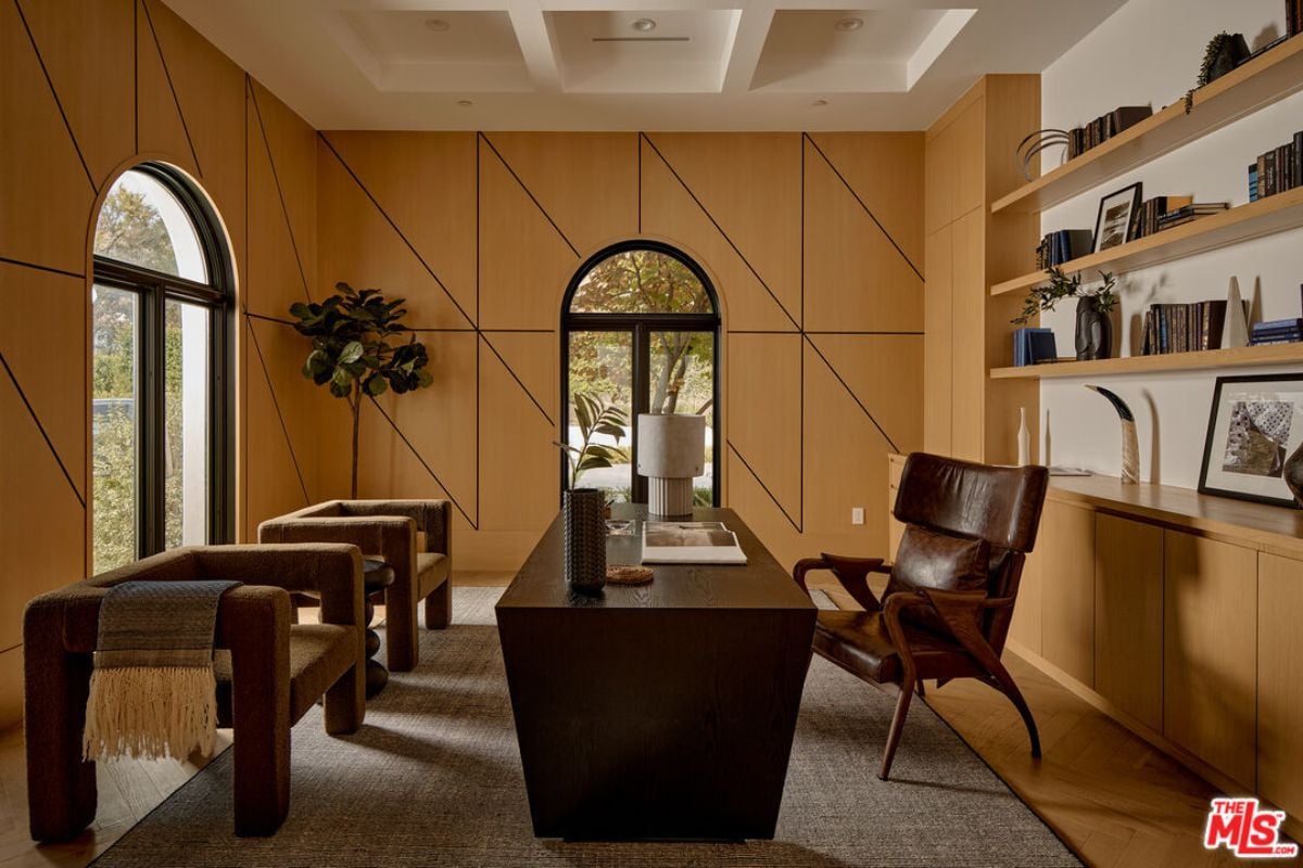 a home office with windows, shelves, desk and chairs