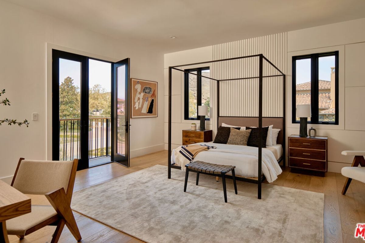 A bedroom with a bed, rug, nightstand, and windows.