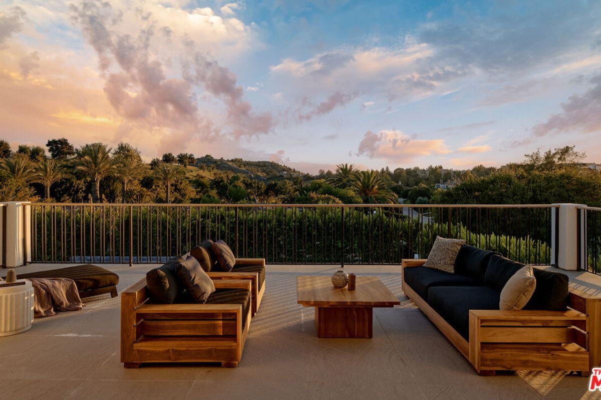 A terrace with a metal fence, couch, chairs, and coffee table.