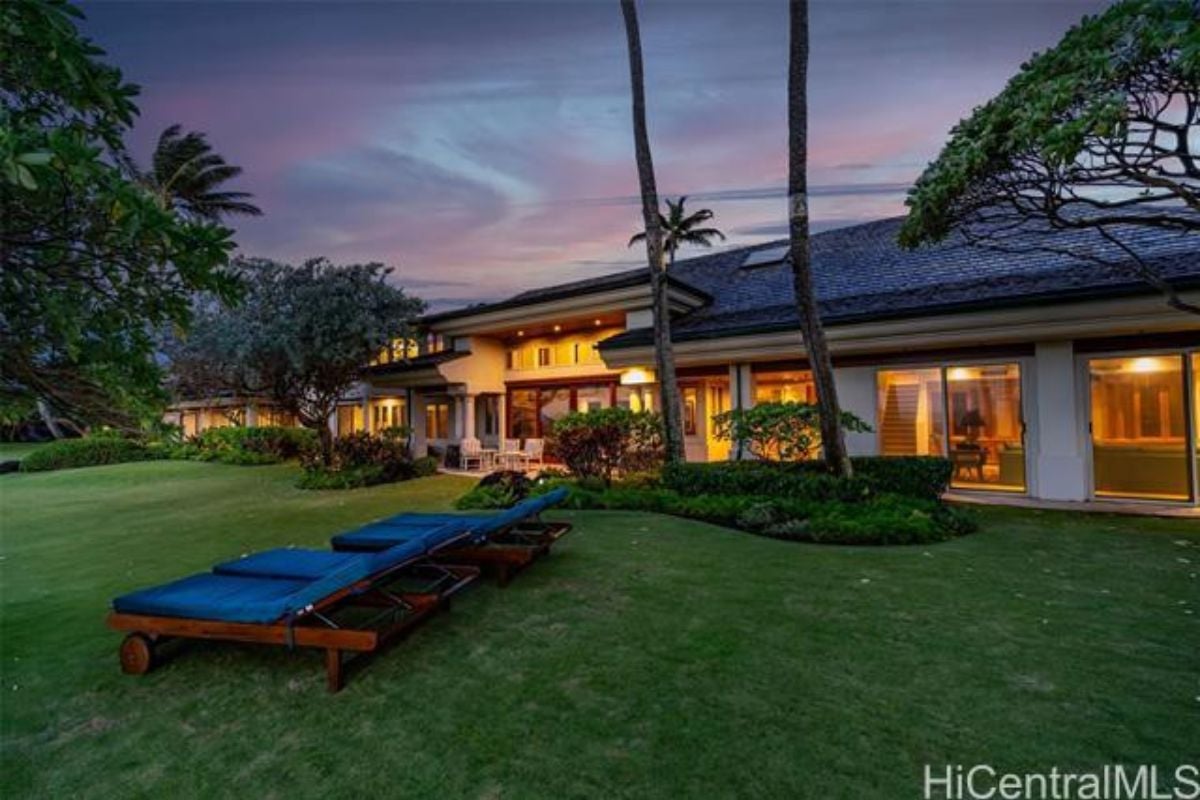 A backyard with chairs, plants, and trees.