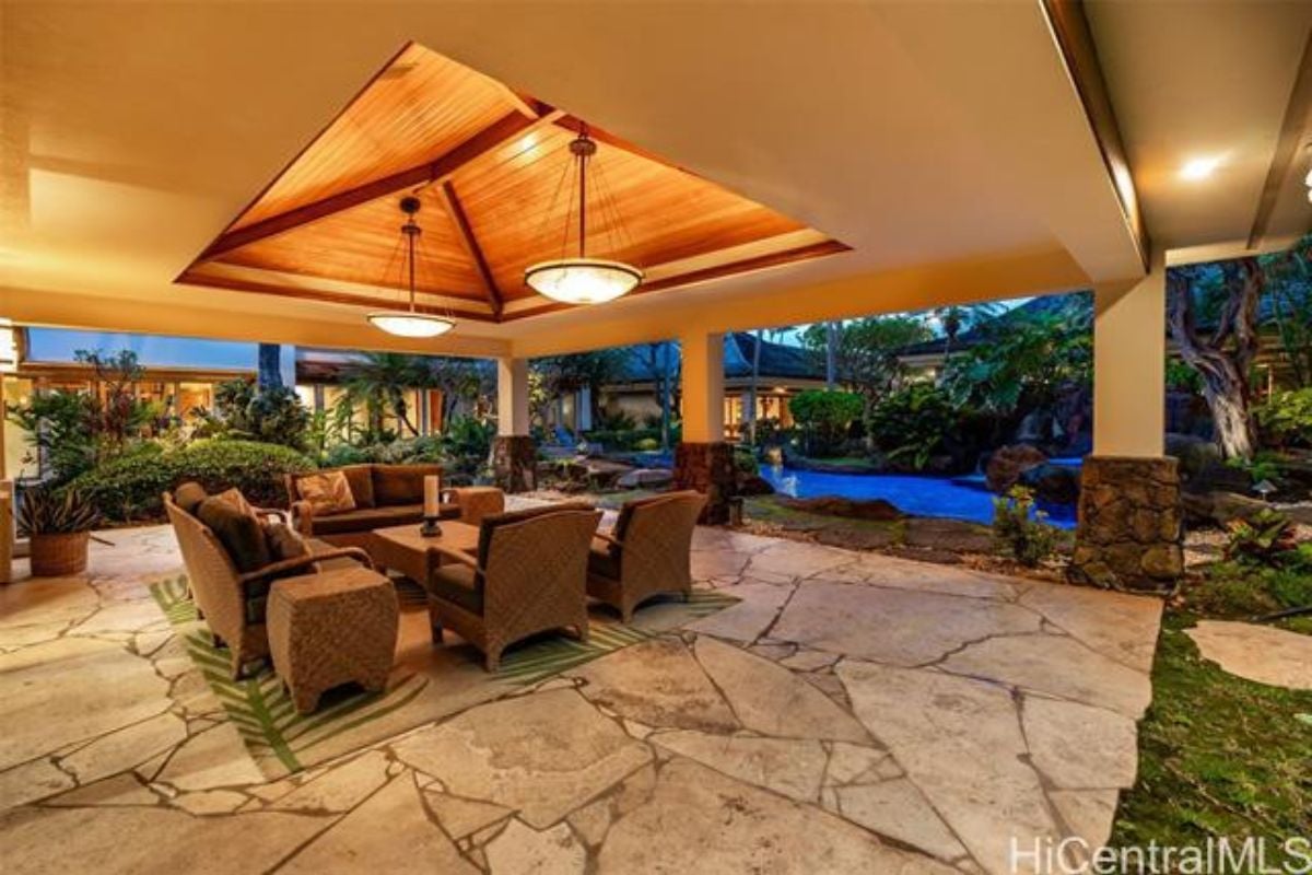 A patio with a rug and center table surrounded by couches.