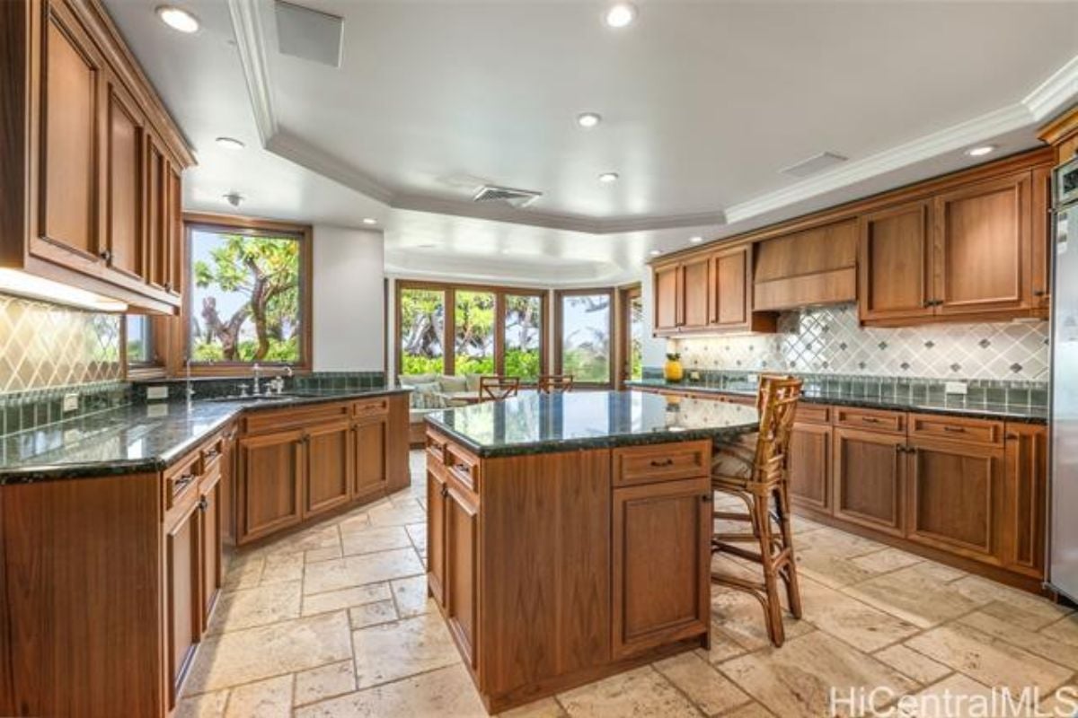 A kitchen with a center island, chairs, countertops, sink, cabinets, and center island.