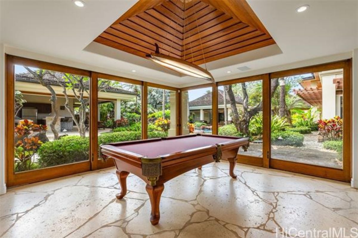 A game room with tall windows and a pool table.