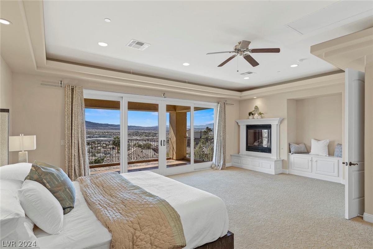 Bedroom with carpet flooring, fireplace and glass doors.