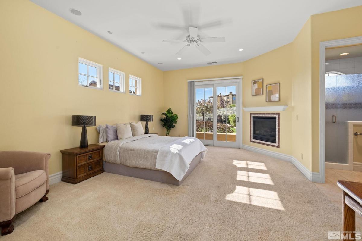 Bedroom with carpet floors, glass door and a fireplace.
