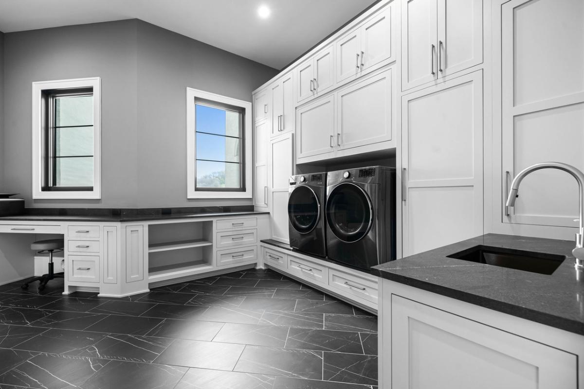 Laundry room with a sink and white cabinets.