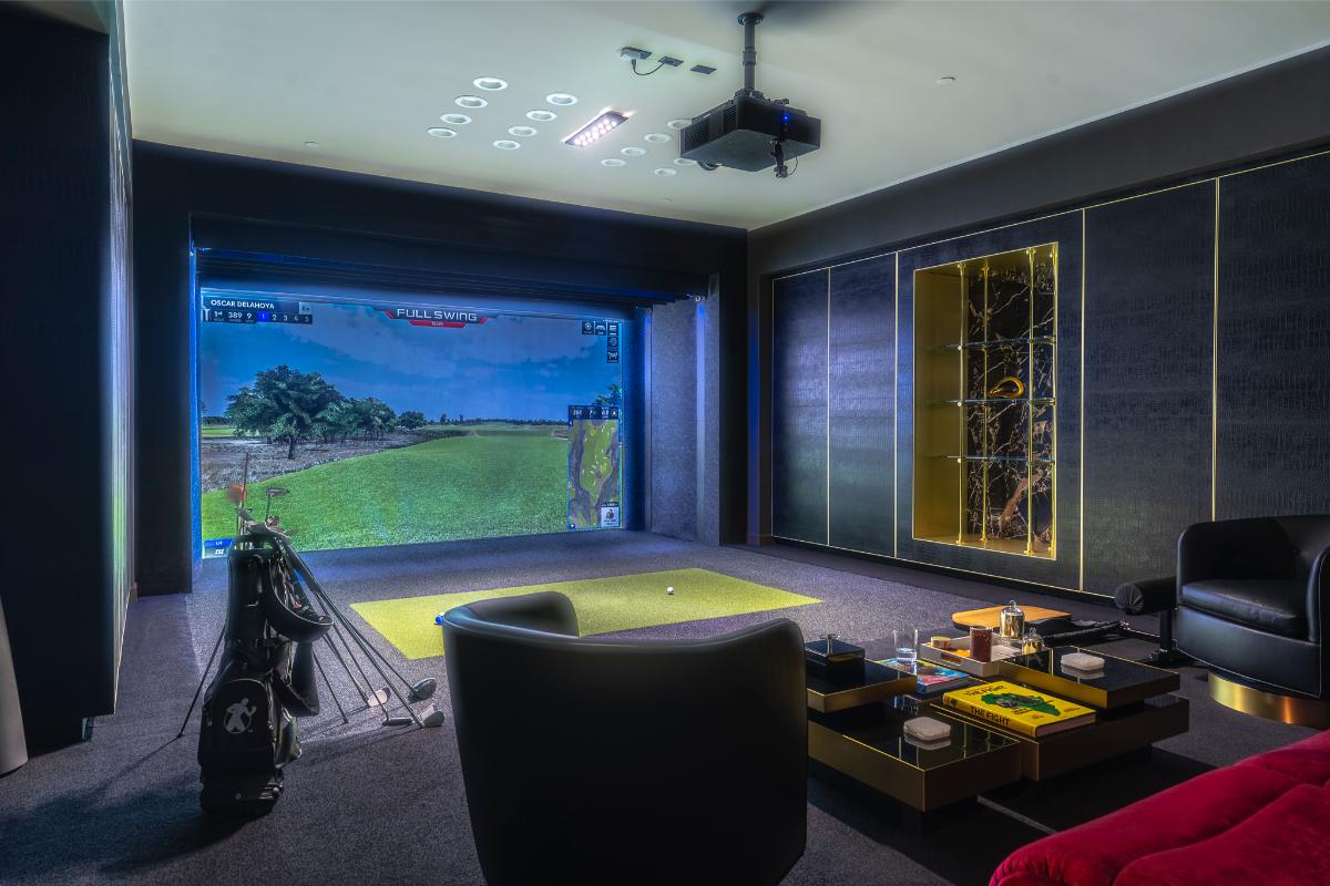 Golf simulator room with a table and couches.