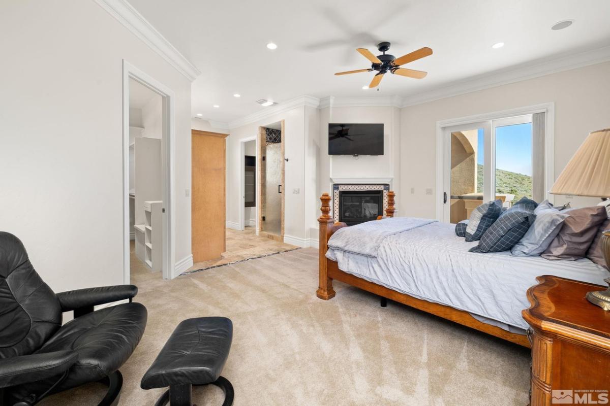 Bedroom with carpet floors, glass door and a fireplace.