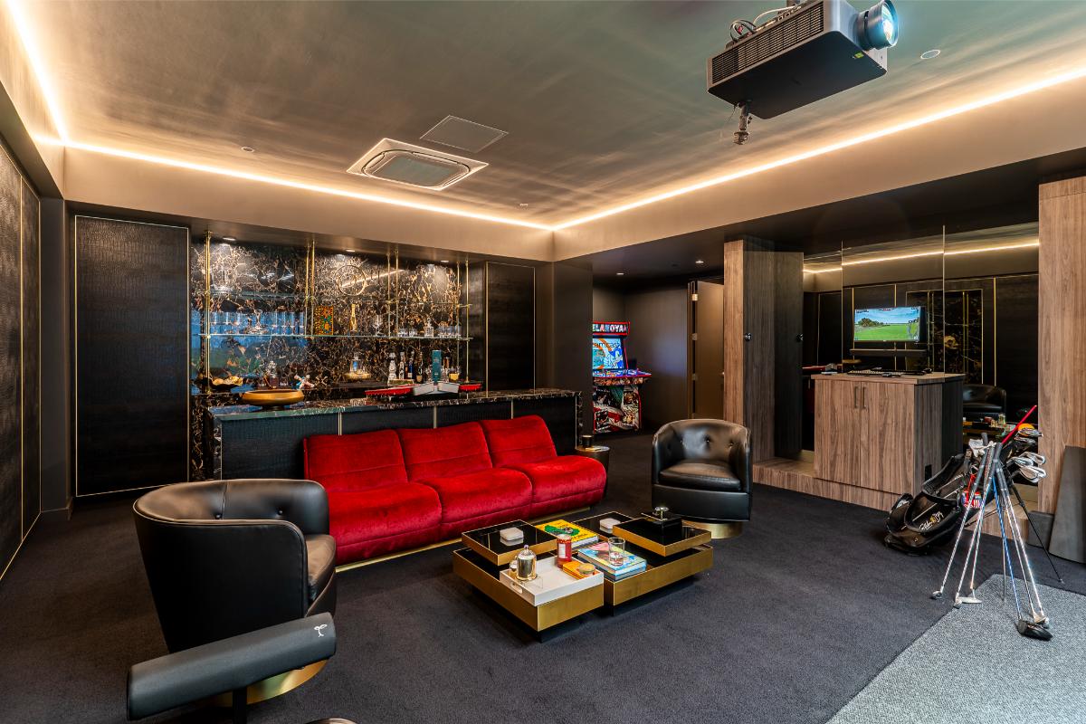 Golf simulator room with a bar, table and couches.