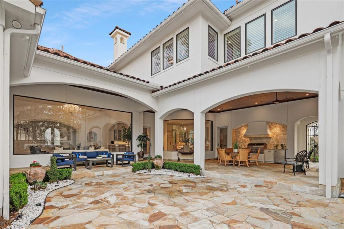 Outdoor living space with tables, chairs and grill area.