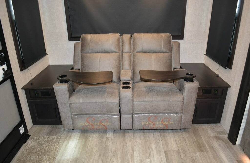 Living area with theater seats flanked by wooden side tables.