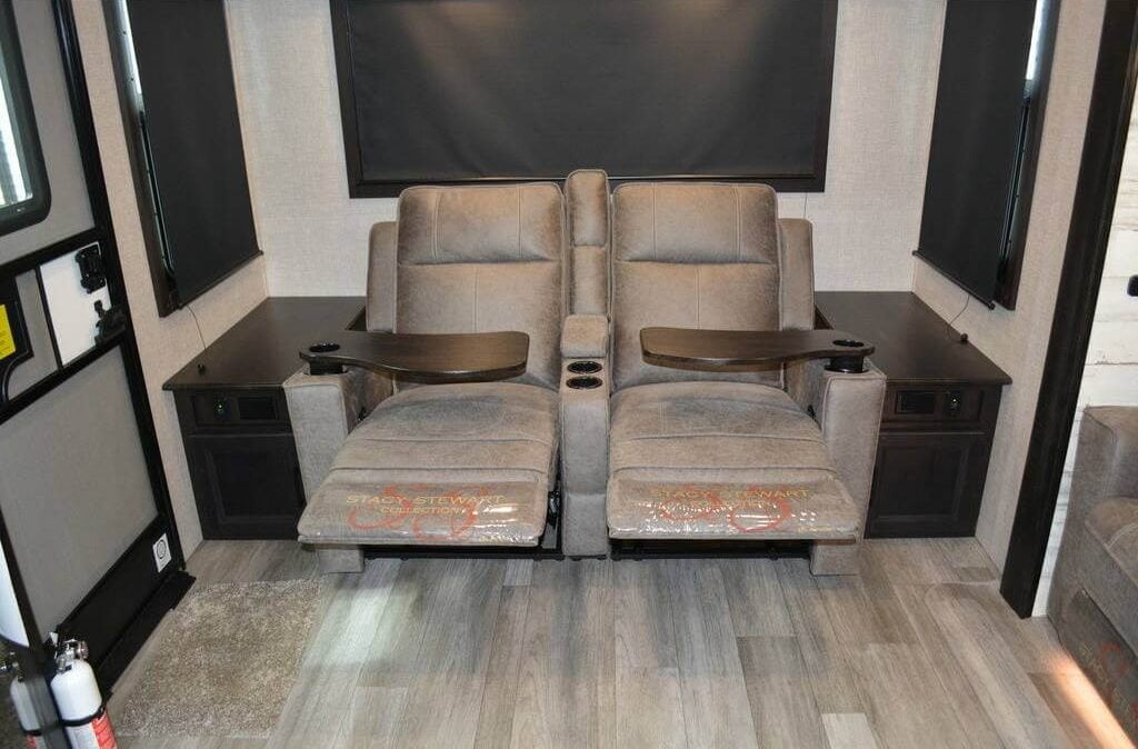 Living area with theater seats flanked by wooden side tables.