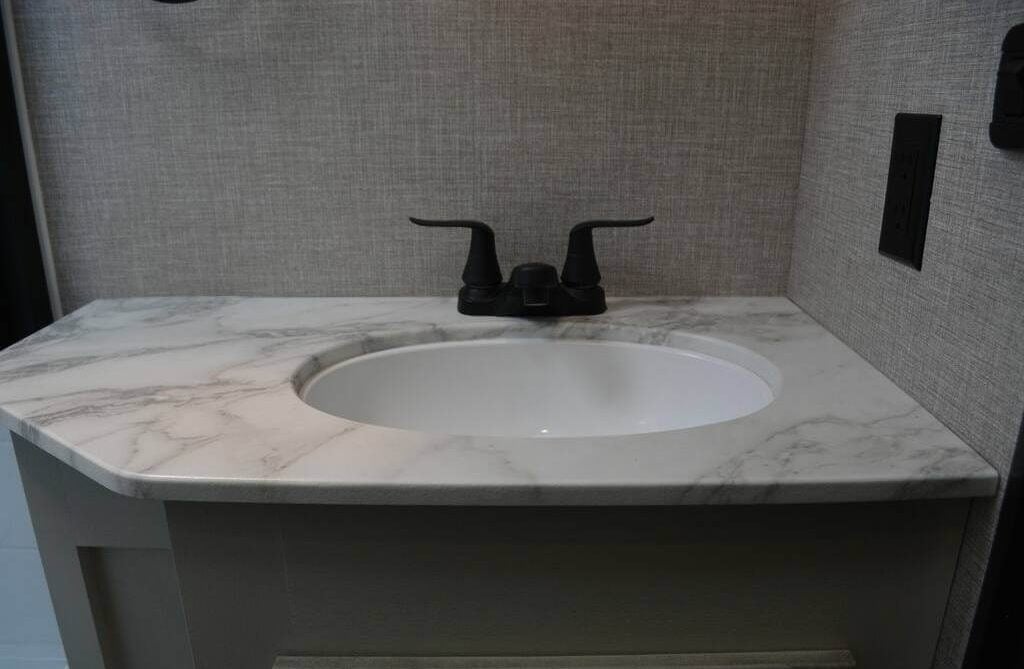 Sink vanity with a marble countertop and wrought iron fixtures.
