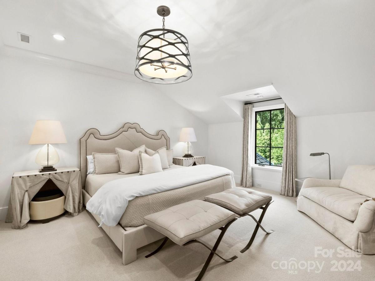 Bedroom with a large bed, couch and carpet flooring.