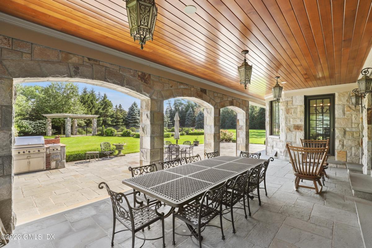 Covered patio overlooking lush gardens and sweeping lawns.