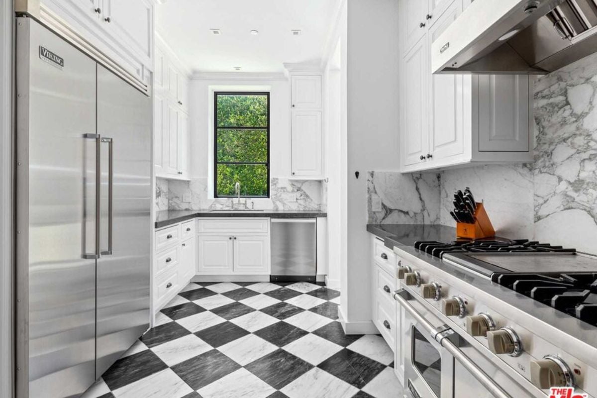 A kitchen with a tiled floor, countertops, cabinets, and kitchen appliances.