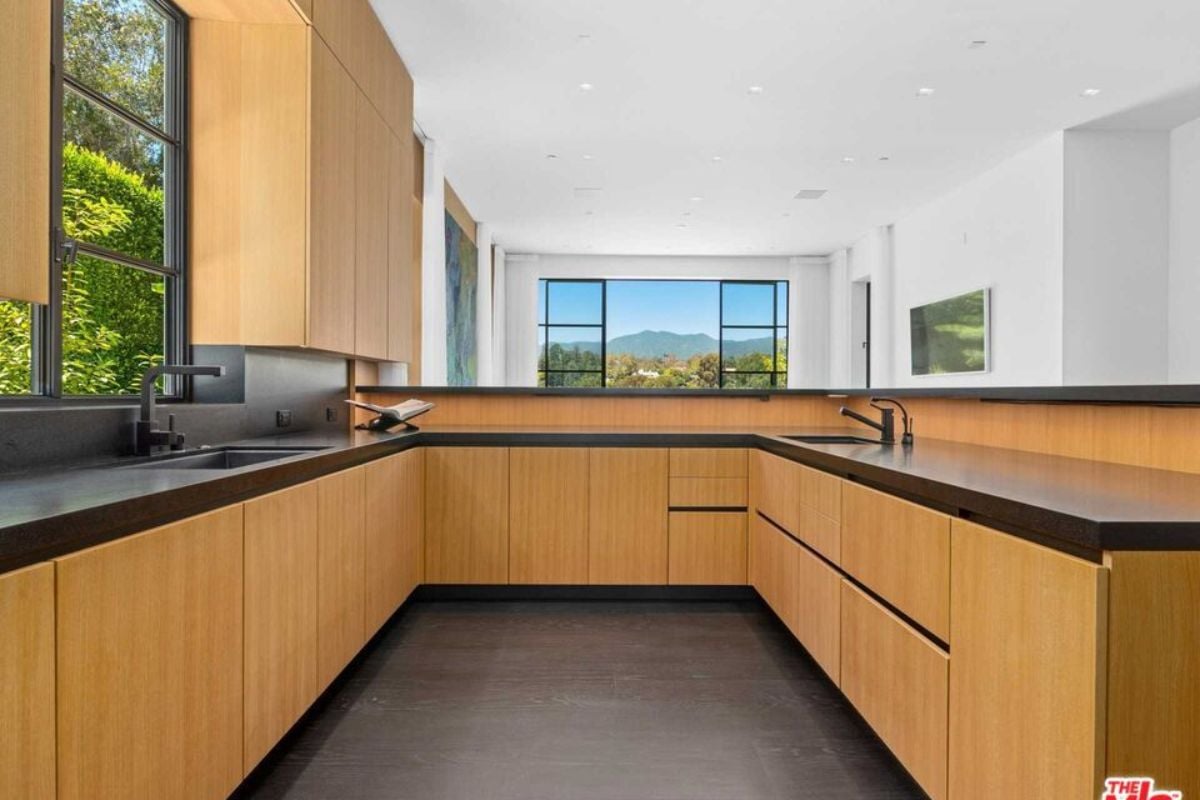 A kitchen with countertops, windows, sink, and cabinets.