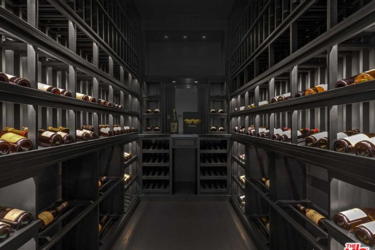 A wine cellar with black wine racks filled with wine bottles.