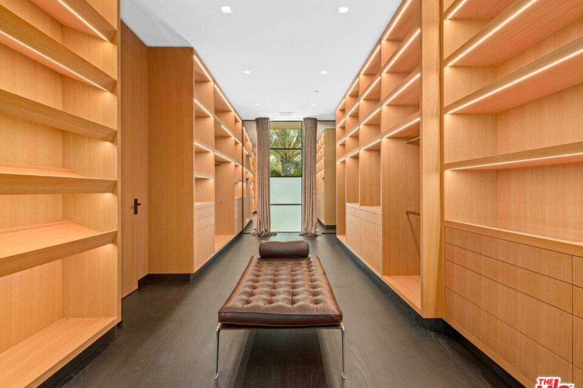A walk-in closet with wooden cabinets, shelves, and a bench.