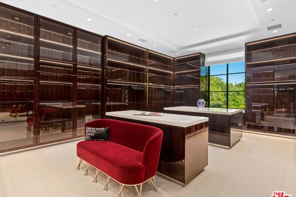 A walk-in closet with islands, red couch, and glass cabinets.