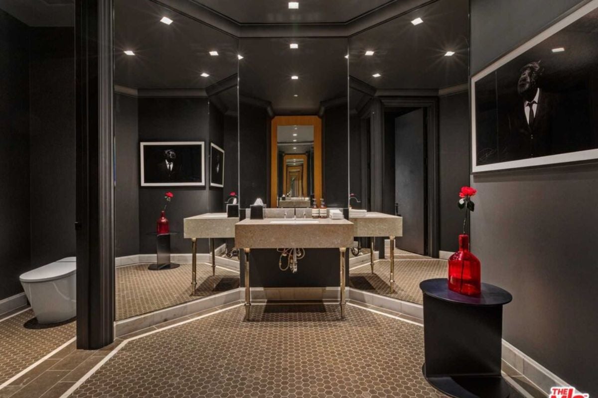 A bathroom with a vanity, tall mirrors, and a toilet.