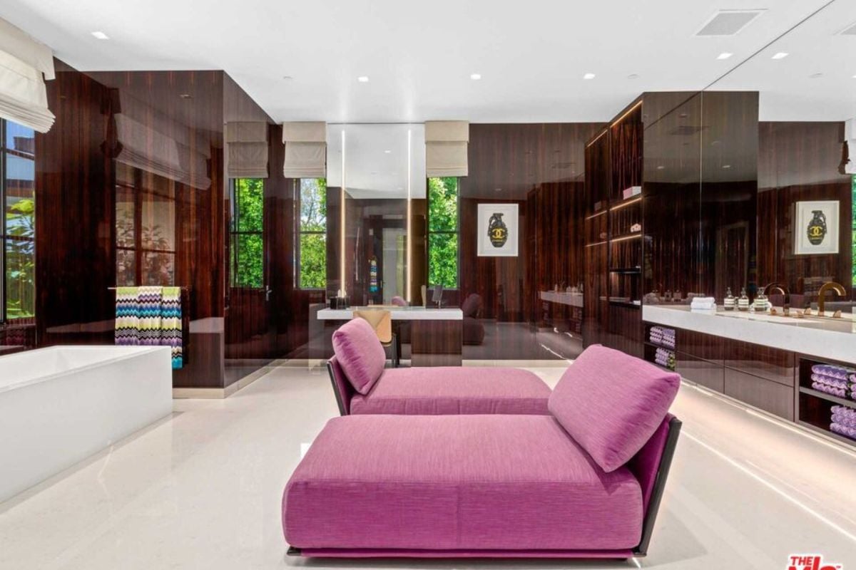 A bathroom with purple couch, countertops, cabinets, a mirror, and a bathtub.
