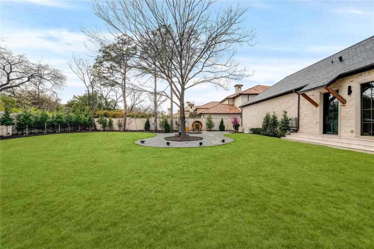 Backyard of the house with a large green lawn.