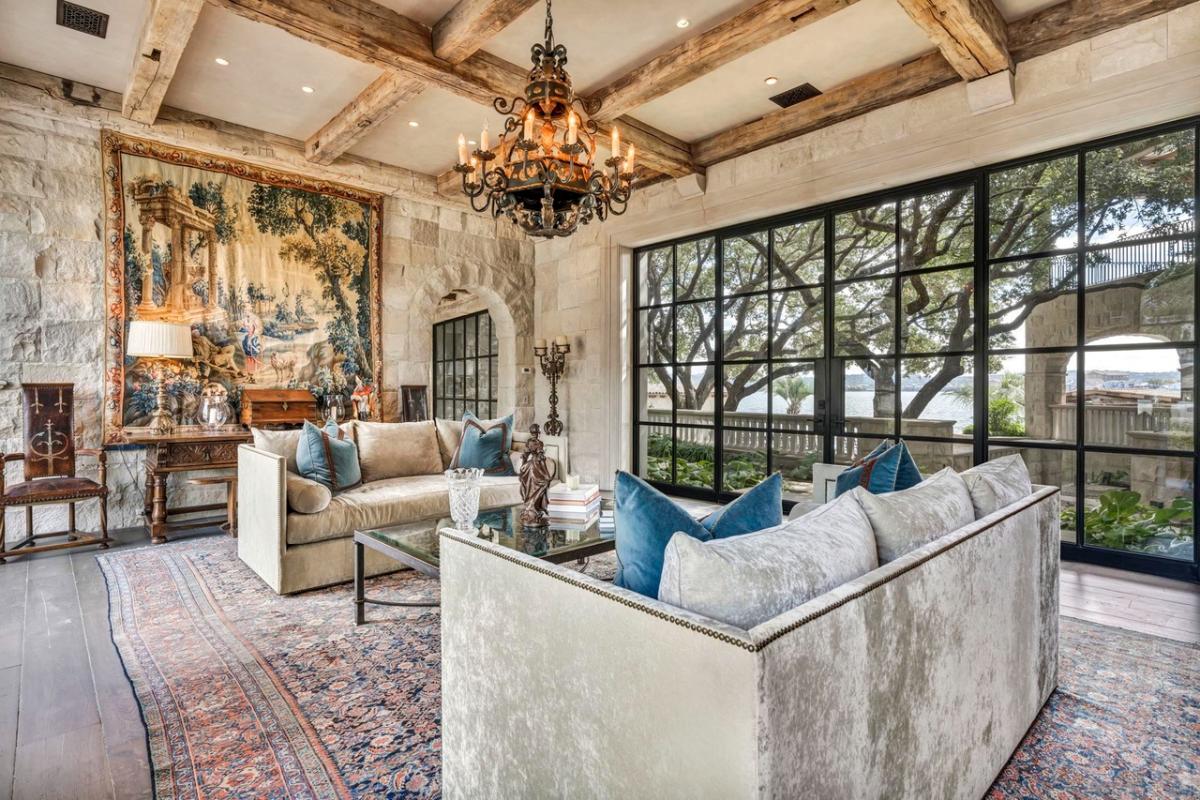 Living room with sofas, chandelier and wood ceiling beams.