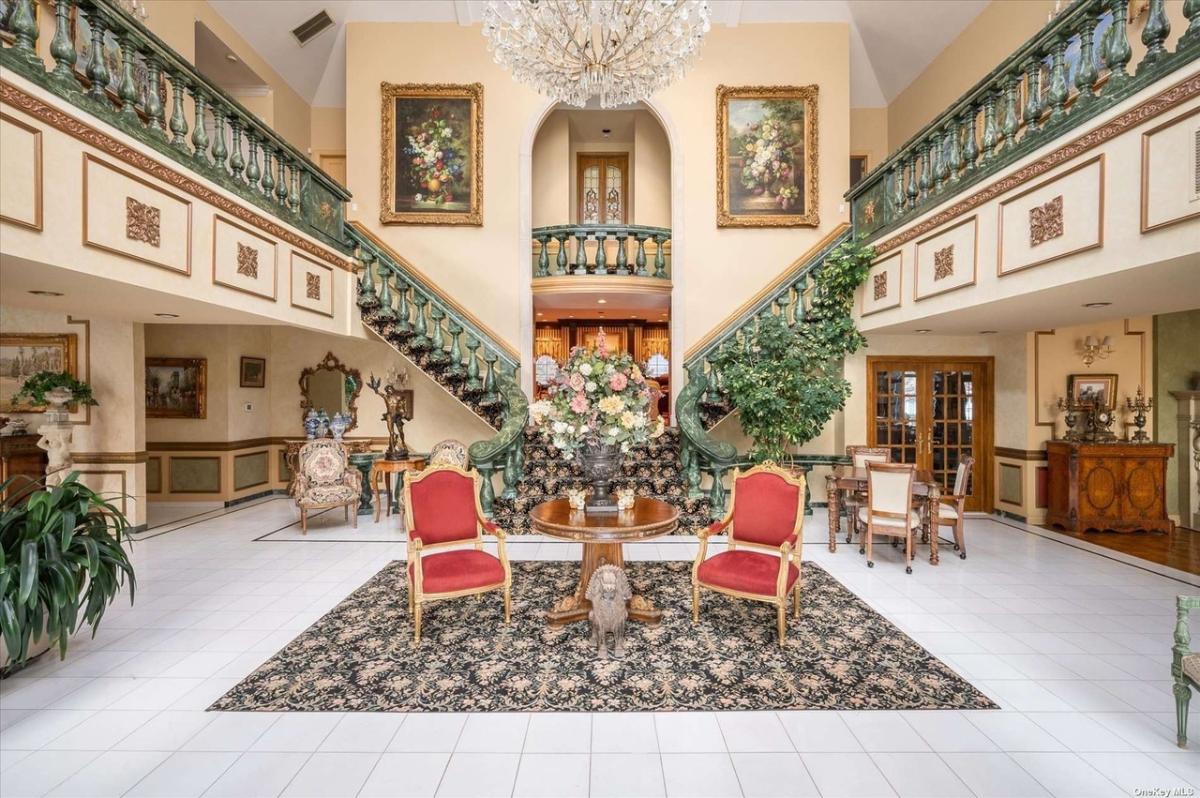 Foyer with a chandelier, table, chairs and staircase.